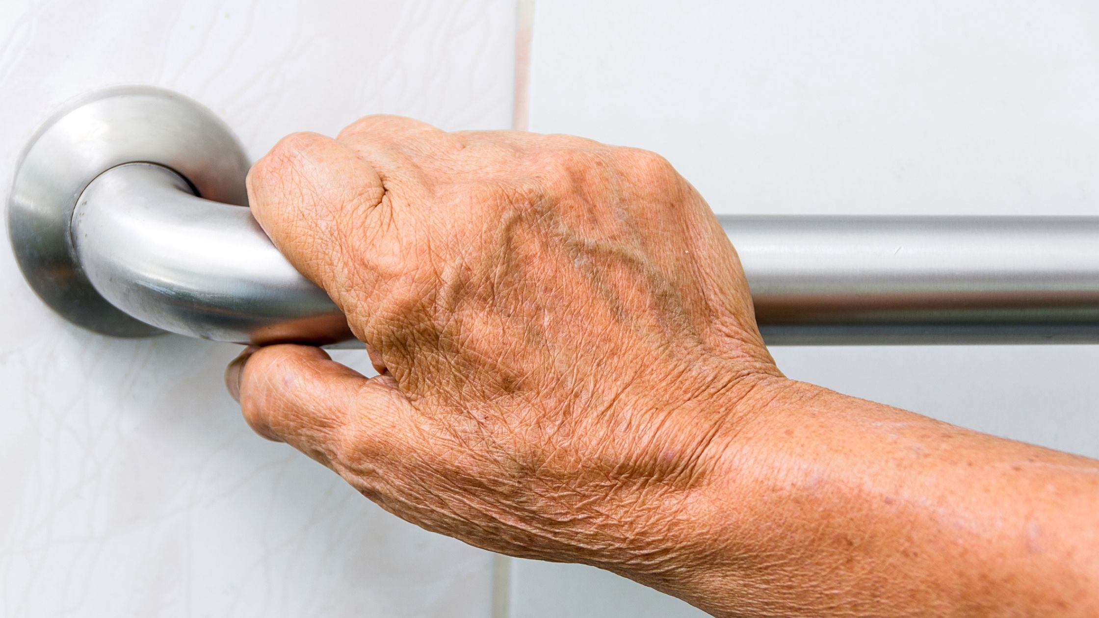 a older woman's hand on a grab rail