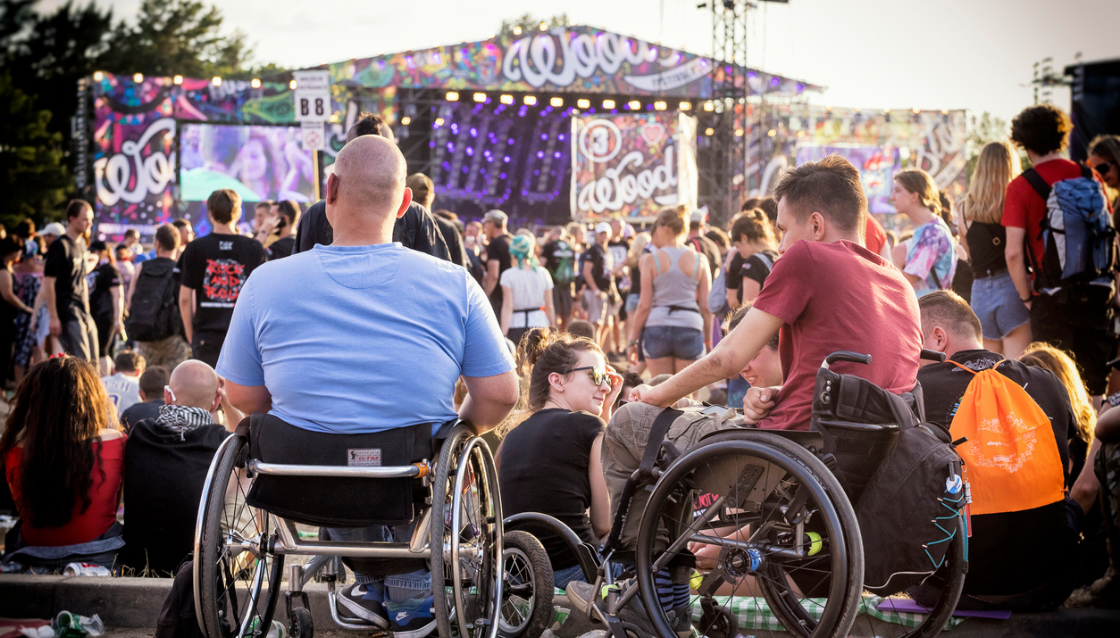 Image of two men in wheelchairs amongst the crowd at an outdoor festival.